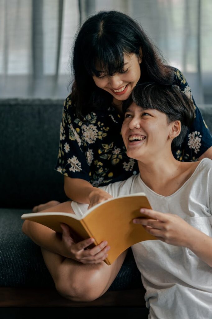 Happy couple enjoying quality time reading indoors, sharing smiles and laughter.